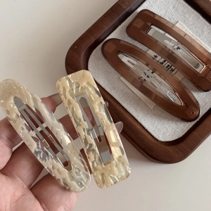 Detail view of four pieces marble and amber brown acetate hair clips on a tray