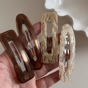 Close-up of four-piece hair clip set in coffee and marble acetate on a white plate