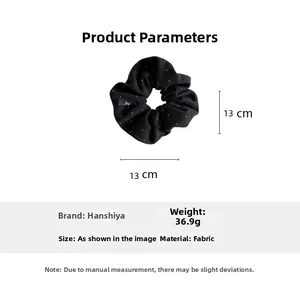Détail d'un chouchou noir à pois avec un diamètre de 13 cm et une texture en tissu