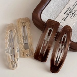 Detail view of 4-piece vintage resin hair clips in marble beige and amber colors