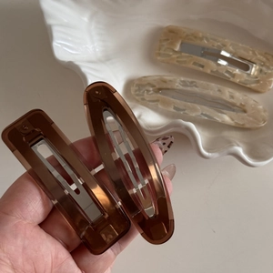 4-piece retro brown and cream marble acrylic hair clip set shown on a shell tray