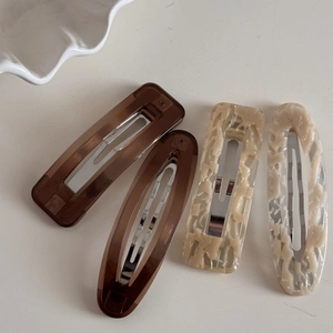 Close-up of four brown and marble resin hair clips with metallic silver BB pins