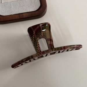 Detail shot of vintage plaid hair claw clip in red and green acetate texture