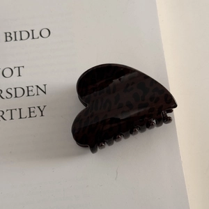 Detail of heart-shaped leopard print hair claw clip made of glossy acetate material