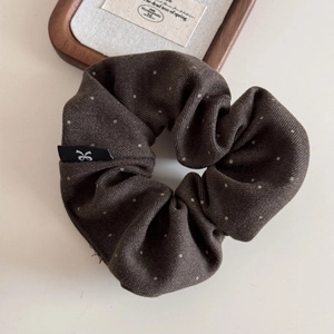 Détail du tissu chouchou marron foncé à pois avec étiquette et texture vintage chic