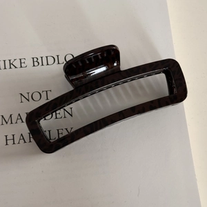 Detailed macro view of a glossy leopard print hair claw clip on a white background card