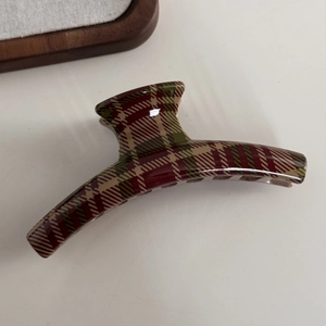 Detailed top view of a large tartan hair claw clip with glossy red and green plaid pattern