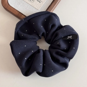 Gros plan sur chouchou bleu marine à pois avec détail d'étiquette logo petit nœud
