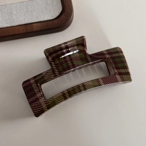 Detailed macro view of large glossy resin hair claw with red and green plaid pattern