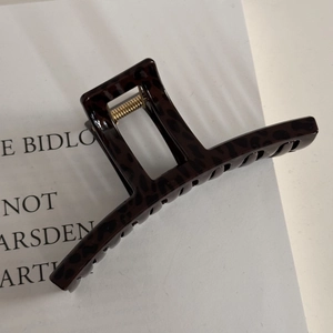 Macro shot of large square leopard print hair claw clip with golden metal spring detail