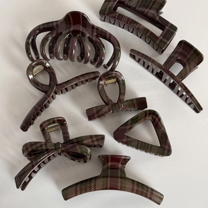 Detail view of 7 assorted hair claws featuring dark green and brown plaid check pattern