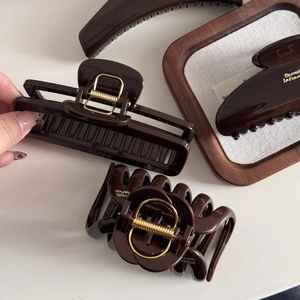 Detail of dark chocolate resin hair claws with gold-tone accents and glossy finish