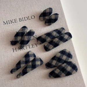Détail de pinces à cheveux vintage en tissu à carreaux bleu marine sur un livre