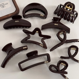 Detailed view of coffee brown resin hair claw clips with elegant gold label lettering