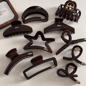 Detailed top view of chocolate brown hair claws with gold logo and various geometric shapes