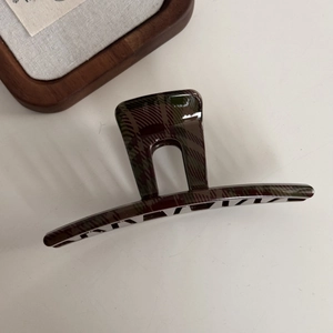 Detailed view of dark green and brown plaid hair claw clip with glossy finish and wood decor
