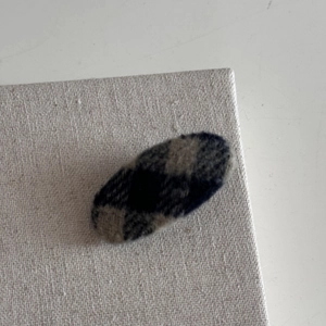 Gros plan sur la barrette ovale en tissu à carreaux bleu marine au style vintage