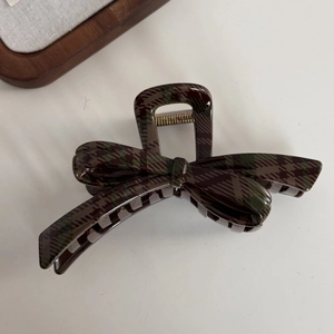 Macro detail of a classic dark plaid bow hair claw clip with a strong metal spring mechanism