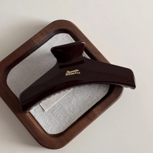 Macro view of chocolate brown hair claw clip with golden text and glossy finish