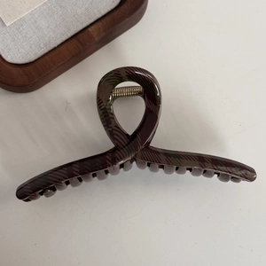 Macro shot of large dark green plaid hair claw clip with glossy finish and metal spring