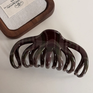 Macro shot of dark red and green plaid pattern hair claw clip with glossy resin finish