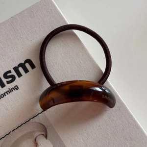 Detail of high-elasticity dark brown hair tie with amber tortoiseshell acrylic decoration