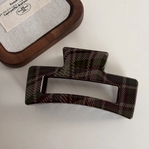 Macro detail of large square hair claw clip featuring vintage dark green plaid pattern