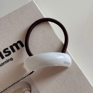 Macro view of minimalist coffee brown elastic hair tie with white acrylic detail