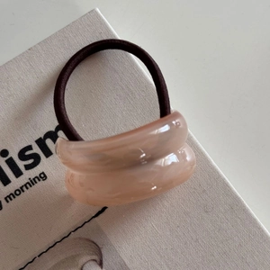 Close-up of semi-transparent lotus pink resin hair ring with elastic band and gold accent