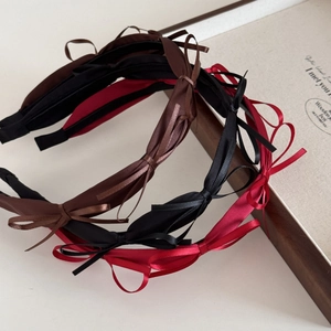 Detail view of thin satin ribbon bow headbands in dark brown, black, and burgundy set