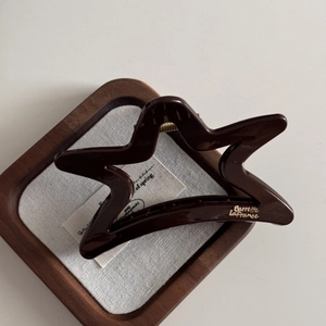 Macro detail of a chocolate brown star-shaped hair claw with gold Barrette La France logo
