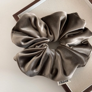 Detailansicht eines Samt-Haargummis in Taupe mit hochwertigem Stoffetikett-Design