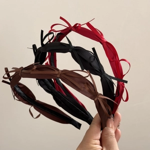 Detailed close-up of three satin bow headbands in red, black and coffee colors
