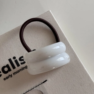 Detailed macro view of white resin hair rings with high-elastic dark brown bands on canvas