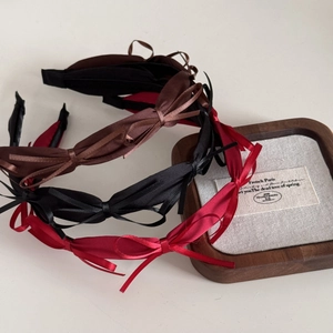 Detail of silk bow headbands in black, brown, and red on a luxury jewelry box