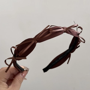 Detailed macro view of dark brown satin bow headband with non-slip fabric lining