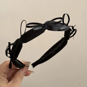 Detailed view of handmade black ribbon bow headband with triple satin decorative accents