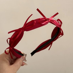 Detailed view of red satin headband featuring four delicate ribbon bows and non-slip lining
