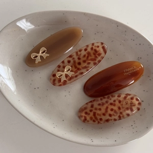 Macro view of French acetate oval hair clips with leopard print and gold bow details
