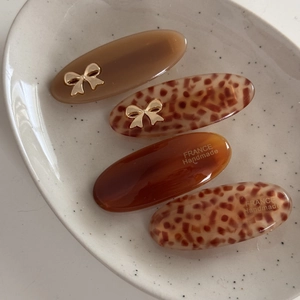 Close-up of brown acetate hair clips with gold bows and France Handmade text in a tray