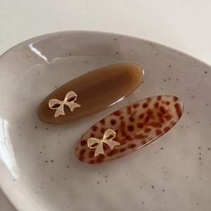 Close-up of tortoise shell and brown acetate hair clips with golden metal bows