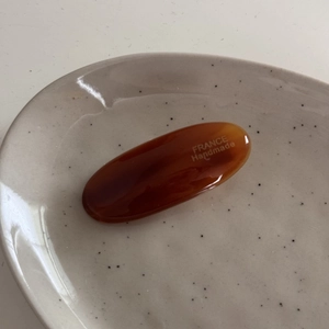 Handmade amber tortoise shell resin hair clip detail with France logo on ceramic plate
