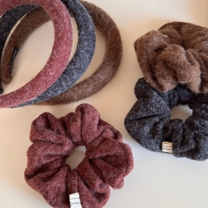 Detail of handmade plush hair accessories in burgundy, grey, and brown winter fabrics