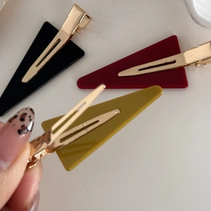 Close-up of geometric acrylic duckbill hair clips in burgundy, yellow and black