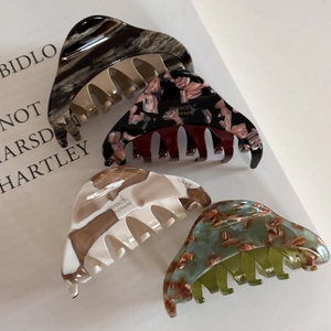 Lot de quatre pinces à cheveux en acétate avec motifs marbrés et floraux sur fond de livre