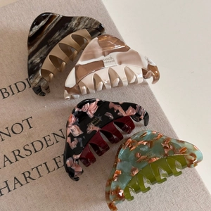 Détail de quatre pinces à cheveux en acétate aux motifs marbrés et floraux avec logo doré