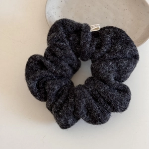 Detailed close-up of dark grey plush wool hair scrunchie with soft fluffy texture