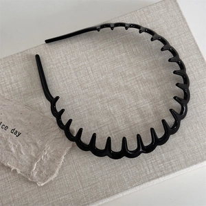 Close-up of a glossy black wavy headband with teeth for hair styling and fixing