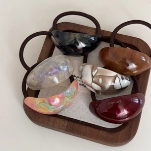 Close-up of 6 acetate hair ties in leopard and marble patterns on a wooden tray