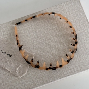 Macro shot of tortoise shell wavy headband with teeth on a textured background
